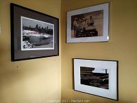 Three framed prints hanging on a yellow wall including the Christo's The Gates winter scene with orange fabric gates, the golfing men photo, and the hands-on-organ photo.