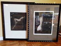 Pair of framed black and white photo prints showing nude female forms, captured from the front. One frame has a waved dark frame with gray mat, the other a simple black frame with white mat.
