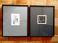 Two framed black and white mezzotint prints side by side on a wooden floor; left print with grey matting, right print with dark matting.