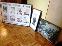 Three framed artworks: large framed poster titled 'ART DE BOIRE LE VIN', tall black and white photo print in black frame, and wood framed oil painting of Paris scene with canal and trees.