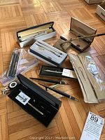 Overview of all items including boxed pens, desk pen with marble base, and wristwatch on floor