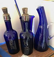 Two decanters with metal-topped stoppers and cobalt glass carafe visible behind