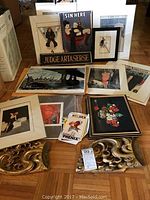 Wide view of assortment showing wooden sign, multiple matted prints, framed print and postcards spread on floor