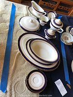 Overview of two oval platters, vegetable bowl, sugar bowl, creamer, gravy boat and small plates on table