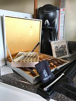 Photo of Krups coffee maker, two steak knife sets in cases, Argento Italia carving knife, and rolling pin on counter
