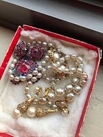 Box containing freshwater pearl necklace, pearl drop earrings and pink/purple crystal brooch with matching earrings