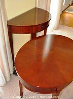 Two tables arranged side by side showing oval table in foreground and half-round console table against wall