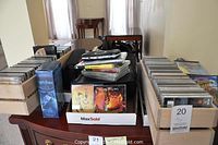 Wide view showing two wooden CD holders filled with CDs, boxed Harry Potter audiobook cassette set, and box containing cassettes and CDs