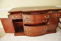 Front and angled view of cherry wood sideboard showing open drawers and cabinets.