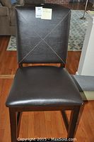 Front view of one chair showing brown faux leather upholstery and wood frame