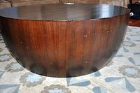 Side view showing the rounded drum shape and dark wood finish with minor surface wear and slight nick on edge.