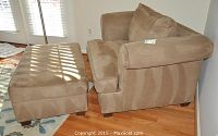 Side view of taupe microsuede armchair and ottoman on hardwood floor