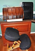 Black upholstered kneeling chair positioned in front of wooden dresser with wooden desk organizer resting on top.