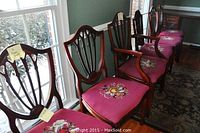 All six matching wooden chairs arranged in a row by a window