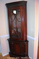 Front view of entire corner cabinet showing overall shape, finish, and door design