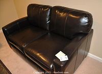 Front view of dark brown leather loveseat showing two seat and two back cushions