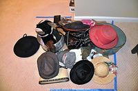 Various hats, handbags, and hat boxes arranged on the floor including felt hats, fabric hats, and straw hat.