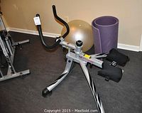 Front-side view of the ab exercise machine with yoga mat and exercise ball behind it.