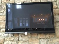 Front view of Panasonic flat screen TV mounted on stone wall