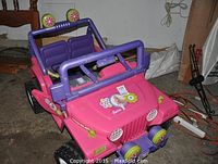 Front three-quarter view showing pink body, purple roll bar, front bumper with dual decorative lights, Barbie decal on hood