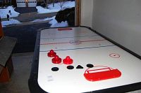 Full view of the KT Sports air hockey table showing red pushers, black pucks, and red goal at one end of the table.