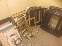 Assortment of wooden picture frames, picture mats, and mounting hardware on carpeted floor
