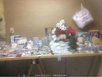 Wide view of the assortment of craft supplies laid out on a table against a pegboard wall including various packages and floral craft items.