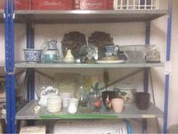 Three shelf metal rack with assorted garden decor items including glass vases, ceramic pots, and decorative plaques.