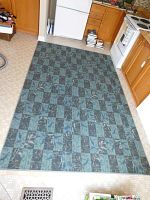 Overall view of blue and navy patterned area rug laid on kitchen floor.