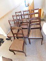 Ten mahogany chairs arranged in a group, showing ladder-back design and striped seats