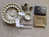Overview of all items: hammered silverplated shell dish with sun face, small silverplated bowl, decorative flower container, creamer, Gaucha knife with sheath, enamelled picture frame and japanned wooden box lid.
