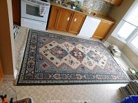 Full view of the full carpet laid out in a kitchen floor, showing the geometric Navajo style pattern and colors.