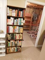 Full view of the tall wooden bookcase filled with multiple shelves of books.
