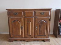 Front view of wood kitchen buffet showing two drawers on top and two doors below with brass hardware.