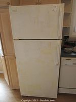 Front view of white Kenmore top freezer refrigerator showing wear and discoloration.