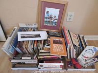 Wide view of assorted mixed lot of approximately 30 books including titles related to animals, Toronto, art, and music, plus a framed art print and decorative items