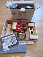 Overall lot contents laid out including Projecta E-9680 projector box, slide trays, metal balls in box, art print, trays, and wooden box