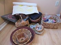 Woven baskets, candle holders, yarn craft decorations, and a decor bag arranged on the floor in a corner.