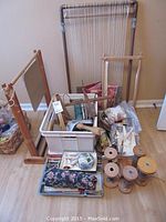 Wide view of the lot showing multiple wooden weaving frames, spools of yarn, crafting tools, and bags of fabric.