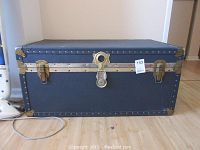Blue storage trunk closed, showing front with central lock and brass hardware