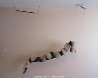 Full view of snake marionette puppet suspended by strings with fur segments and control bars.