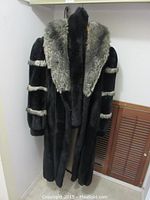 Front angled view of the black jacket showing gray fur collar and arm stripes
