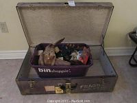 Front view of the open metal trunk showing the plastic bin filled with decorative items inside.