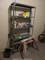 Full view of gray metal storage shelf with tools and various items on shelves, wooden saw horses positioned in front of shelf