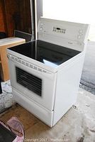 Three-quarter front view of white GE range in garage environment