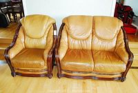 Front view of tan leather armchair and loveseat side by side on hardwood floor