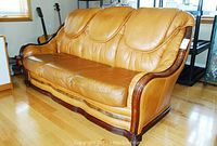 Left-front three-quarter view of entire sofa showing leather upholstery and wood frame