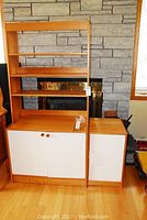 Front view of IKEA shelving and desk unit with wood and white laminate finish, showing upper shelves and cabinet doors.