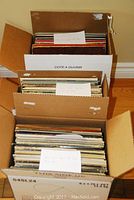 Three large cardboard boxes filled with vintage vinyl records stacked together, showing the volume of the collection.