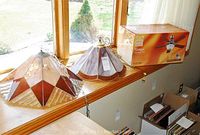 Wide view of two stained glass lampshades and boxed ceiling fan on windowsill under natural light